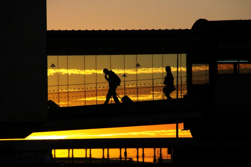 Travelers walking across footbridge in Barcelona Airport, Spain