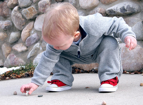 Too Curious Young boy inspecting rock