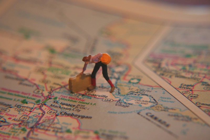 Miniature woman traveler figure standing on paper map