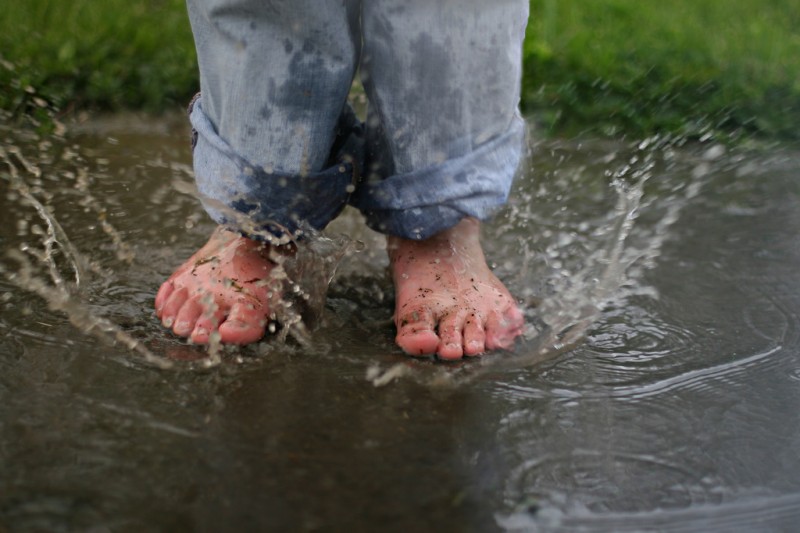 Closeup of feet jumping into puddle