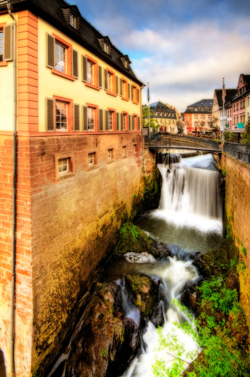 A river flows past an vintage building in Saarburg, Germany