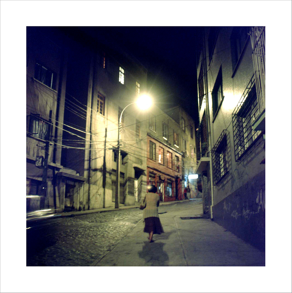 Woman walking at night in streets of ValparaÃ­so, Chile