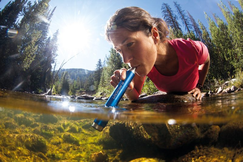 Woman using LifeStraw to purify water while traveling
